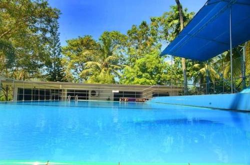 a large blue swimming pool with trees in the background at Kamaro Holiday Resorts (Villa) in Bandaragama