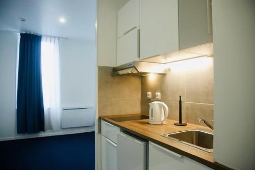 eine Küche mit einer Spüle und einer Arbeitsplatte in der Unterkunft Appart' hôtel 7 sensation in Bougival