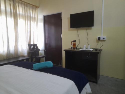 ein Hotelzimmer mit einem Bett und einem Flachbild-TV in der Unterkunft New Dream Homestay in Guwahati