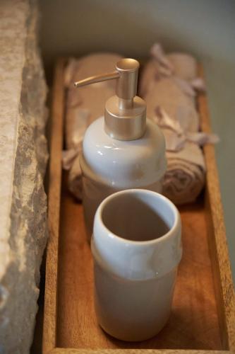 a soap dispenser and a cup on a wooden tray at Dandy Villas Dimitsana - a family ideal charming home in a quaint historic neighborhood - 2 fireplaces for romantic nights in Dhimitsana