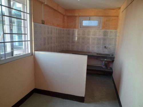 ein kleines Zimmer mit einer weißen Wand und einem Fenster in der Unterkunft New Dream Homestay in Guwahati