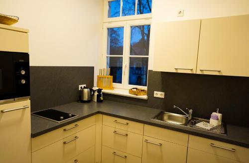 a kitchen with white cabinets and a sink and a window at Parkresidenz Lychen, Ferienwohnung 5 in Lychen