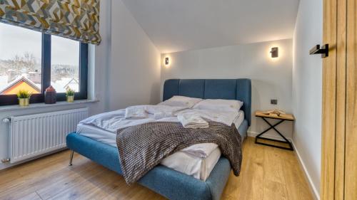 a blue bed in a room with a window at Apartamenty VIP Zdrojowa 6 (deptak) by Royal Aparts in Świeradów-Zdrój