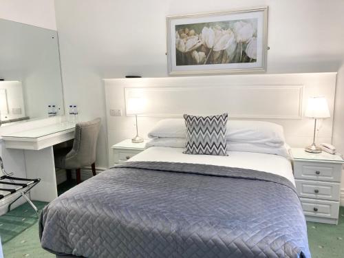 a white bedroom with a bed and a desk and a desk at Dergvale Hotel in Dublin