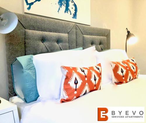 Una cama con almohadas de color naranja y azul. en ByEvo Almar Villa - Comfy Contractor or Large groups property en Glasgow