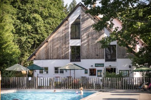 a building with a swimming pool in front of a house at Huttopia de Wattwiller in Wattwiller