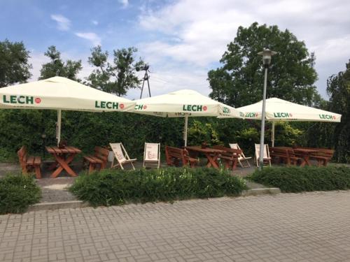 Hotel Na Wzgórzu في غنياو: مجموعة من الطاولات والمظلات في الحديقة