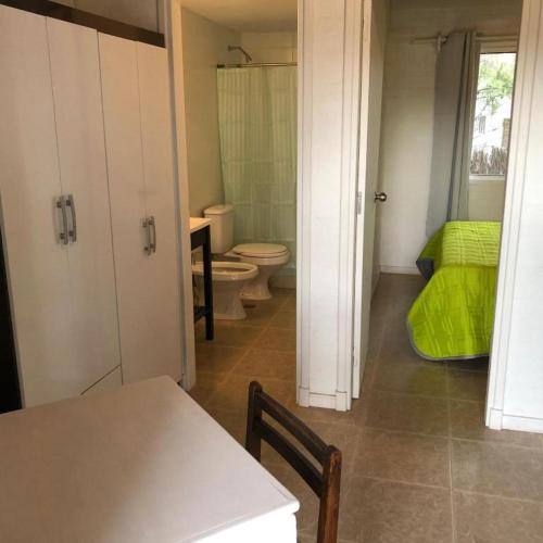 a bathroom with a toilet and a green bed at Hotel Portezuelo in Punta del Este