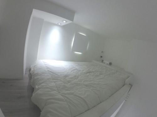 a white bed in a white bedroom with a light at Casa (Loft) para até 4 pessoas. in Cinisello Balsamo