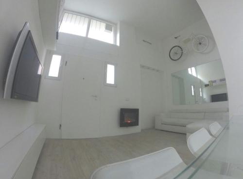 a white living room with a white couch and a clock at Casa (Loft) para até 4 pessoas. in Cinisello Balsamo