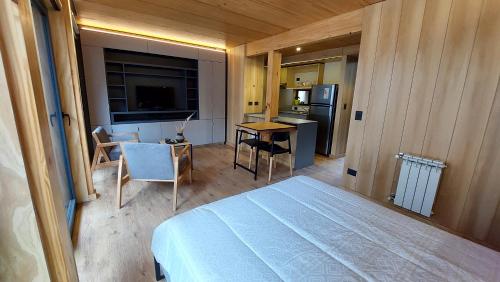 ein Schlafzimmer mit einem Bett und einem Tisch sowie eine Küche in der Unterkunft Monoambiente cálido y cómodo, ubicado en el centro de SMA. 11V5 in San Martín de los Andes