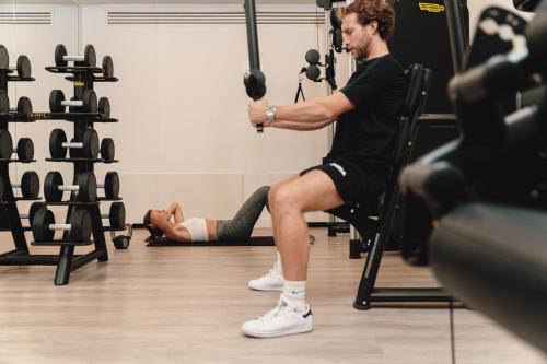 a man sitting in a chair holding a bar in a gym at Hotel Morfeo in Milan