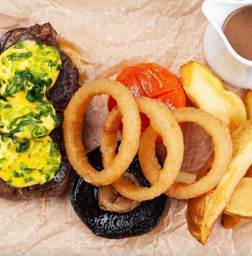 a plate of food with onion rings and a hamburger at Elfordleigh Hotel in Plymouth