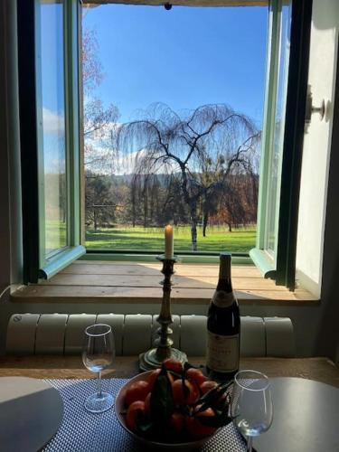 - une bouteille de vin et un bol de fruits à côté de la fenêtre dans l'établissement Maison du petit Poète, à Quarré-les-Tombes