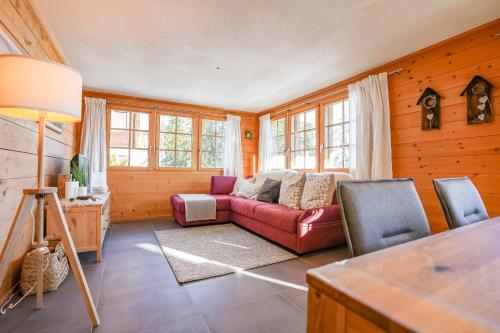 uma sala de estar com um sofá vermelho e algumas janelas em Chumma 22 em Riederalp