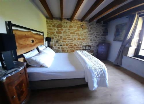 Belle Longere de 10 couchages - lac de vassiviere في Beaumont: غرفة نوم بسرير ابيض وجدار من الطوب