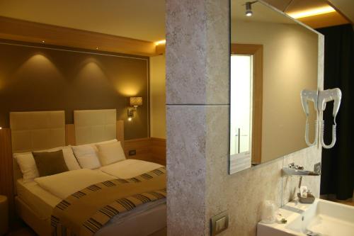 a bedroom with a bed and a sink and a mirror at Hotel Bondi in Livigno
