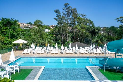 a swimming pool with white chairs and a slide at Atibaia Residence Hotel & Resort in Atibaia