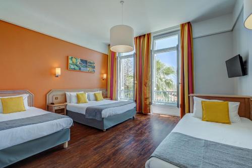 a hotel room with two beds and a window at Hôtel Miléade L'Orangeraie - Menton in Menton