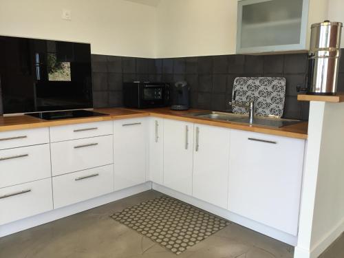 a kitchen with white cabinets and a sink at Ecolodge vue Océan Indien in Saint-Denis
