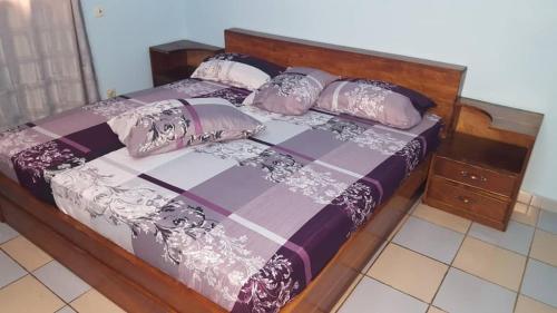 ein Bett mit einem Holzrahmen und Kissen darauf in der Unterkunft Guesthouse Rotimex in Lomé
