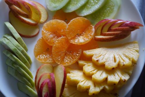 a plate of fruit with oranges and apples on it at North Centre in Cochin