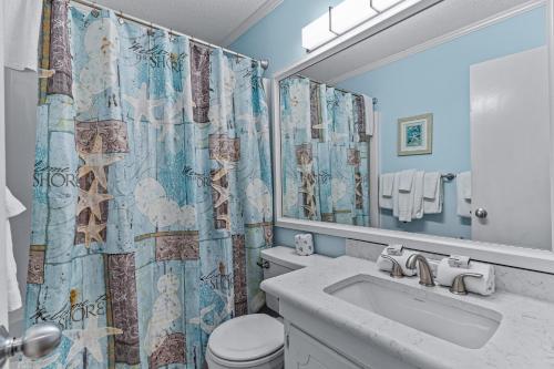 łazienka z umywalką, toaletą i zasłoną prysznicową w obiekcie Ocean Isle Retreat w mieście Ocean Isle Beach
