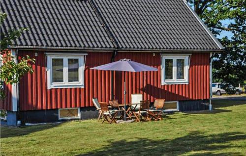 a red house with a table and chairs and an umbrella at Gorgeous Home In Laholm With Heated Swimming Pool in Laholm