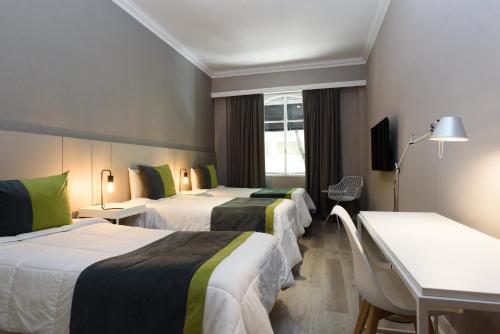 een hotelkamer met drie bedden en een televisie bij SuMa Recoleta Hotel in Buenos Aires