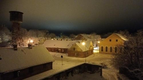 un village recouvert de neige la nuit avec des lumières dans l'établissement Amanda's apartment, à Kuldīga