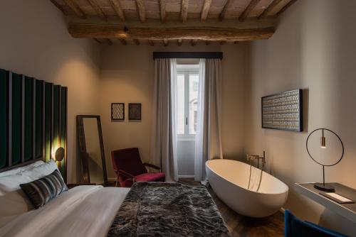 a bedroom with a tub and a bed and a chair at Times Suites in Perugia