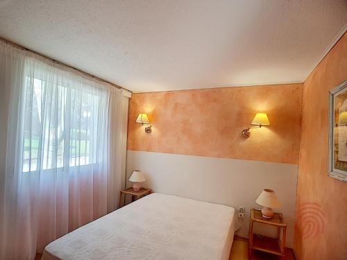 um quarto com uma cama branca e uma janela em Appartement Lamalou-les-Bains, 2 pièces, 2 personnes - FR-1-451-24 em Lamalou-les-Bains