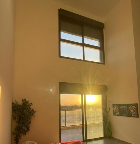 a window in a room with the sun shining through it at פנטהוז ונוף עוצר נשימה, שקט אפשרות בקומה העליונה לחדר משרד הפנטהוז מיועד לאורחים in Bet Shemesh