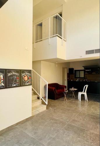 a living room with a staircase and a red couch at פנטהוז ונוף עוצר נשימה, שקט אפשרות בקומה העליונה לחדר משרד הפנטהוז מיועד לאורחים in Bet Shemesh