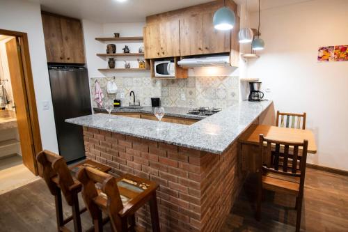 cocina con encimera, mesa y sillas en Casa Lucas - loft espaçoso com jardim e churrasqueira, en Petrópolis