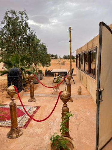 a patio with a table and a red rope at Erg Chebbi Sahara Camp in Merzouga