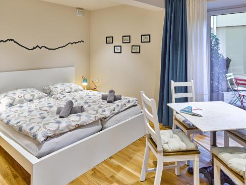 Innheaven Apartments في إنسبروك: غرفة نوم بسرير وطاولة وكراسي