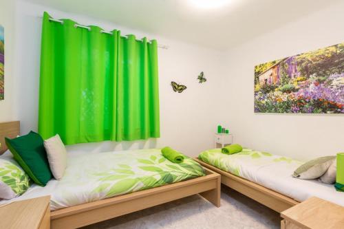 - 2 lits dans une chambre avec des rideaux verts dans l'établissement Apartamento Casa de Campo, à Madrid