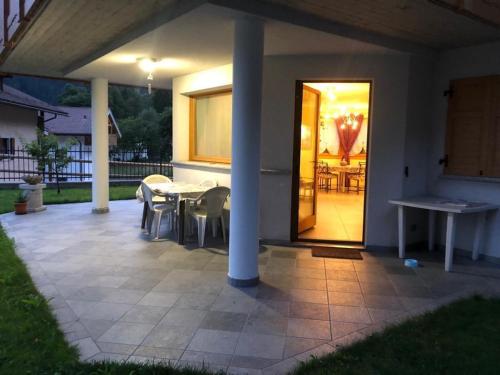 a patio with a table and chairs and a table and a door at casa Olivieri in Carisolo