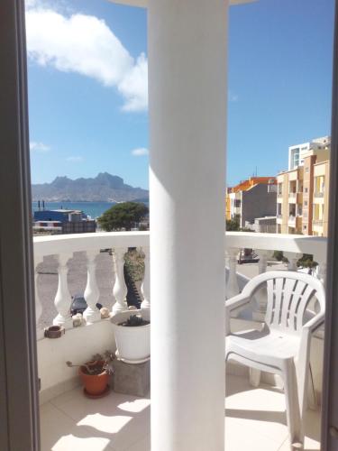 a balcony with a white chair and a view of the ocean at Appart Chris Mindelo in Mindelo