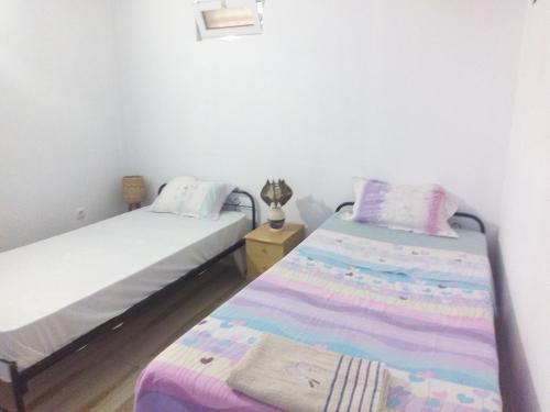 two beds in a small room with purple and pink sheets at Appart Chris Mindelo in Mindelo