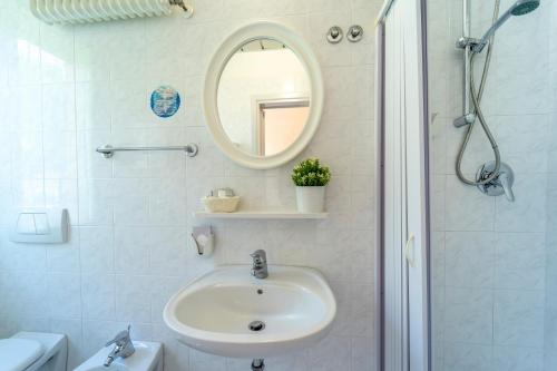 W białej łazience znajduje się umywalka i lustro. w obiekcie Hotel Romagna w mieście Riccione