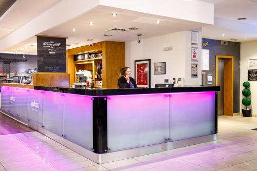 a woman standing behind a bar in a restaurant at Mercure Glasgow City Hotel in Glasgow
