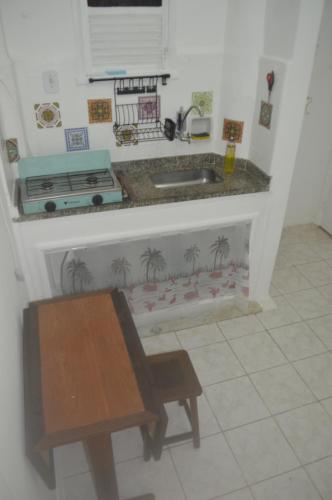 uma cozinha com um lavatório, uma mesa e um banco em Conforto de copa na quadra da praia no Rio de Janeiro