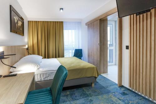 a hotel room with a bed and a desk and chairs at Hotel Gromada Łomża in Łomża