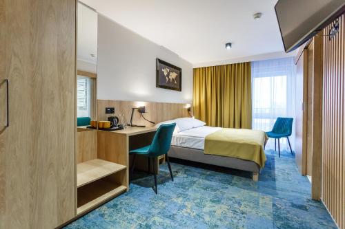 Habitación de hotel con cama, escritorio y sillas en Hotel Gromada Łomża, en Łomża