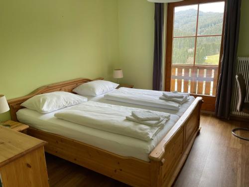 um quarto com uma cama de madeira com lençóis brancos e uma janela em Hotel Ötscherblick em Lackenhof