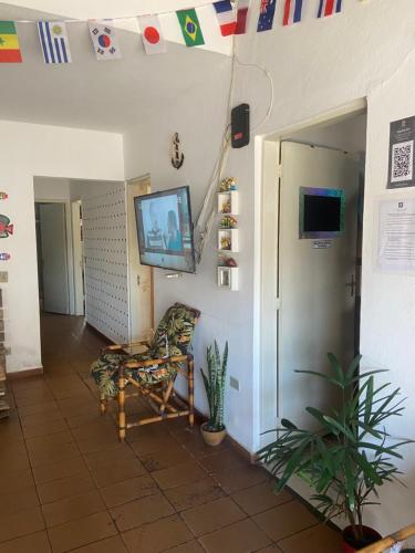 a hallway with a room with a television and a chair at Casa da Si Hostel in Ubatuba