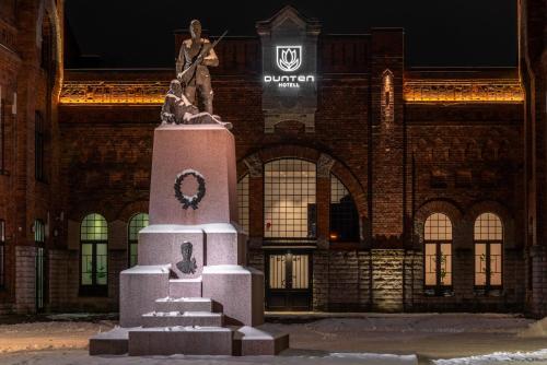 una estatua delante de un edificio por la noche en Dunten Hotel, en Tallin