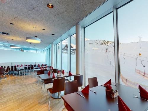 a restaurant with tables and chairs and large windows at Hotel Ski Austria St.Christoph a.A. in Sankt Christoph am Arlberg